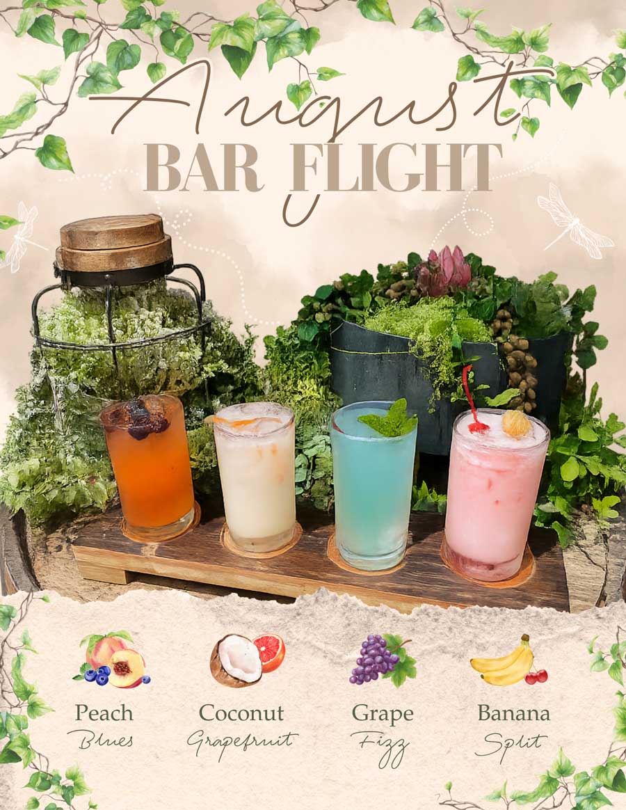 Four colorful summer cocktails on a wooden tray, surrounded by lush green plants and decorations.
