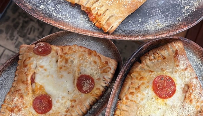 Three plates each with a Reel Java Dinner Menu pizza slice, folded, baked, and topped with pepperoni.